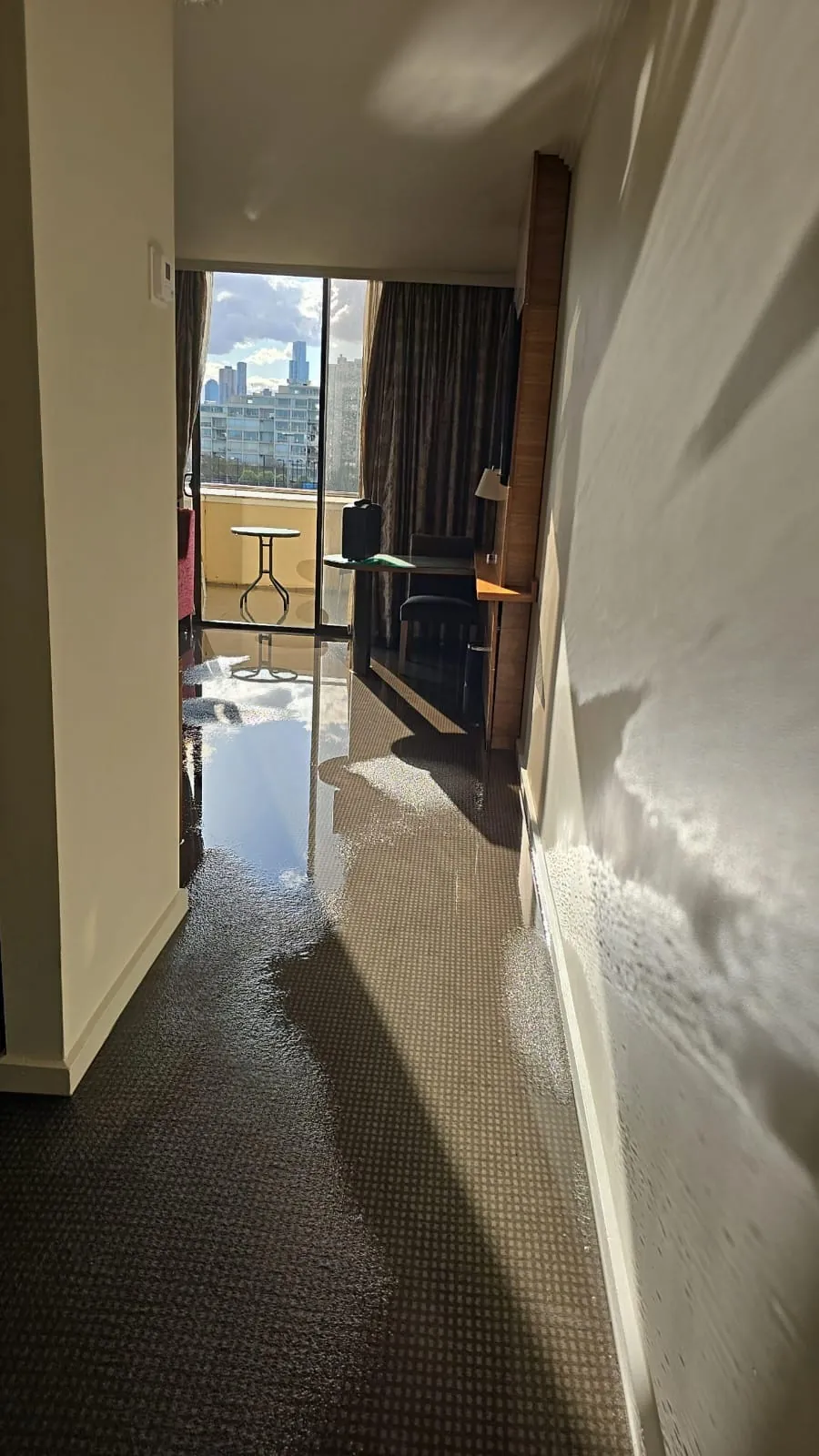 Water across a guest room floor towards the balcony doors.